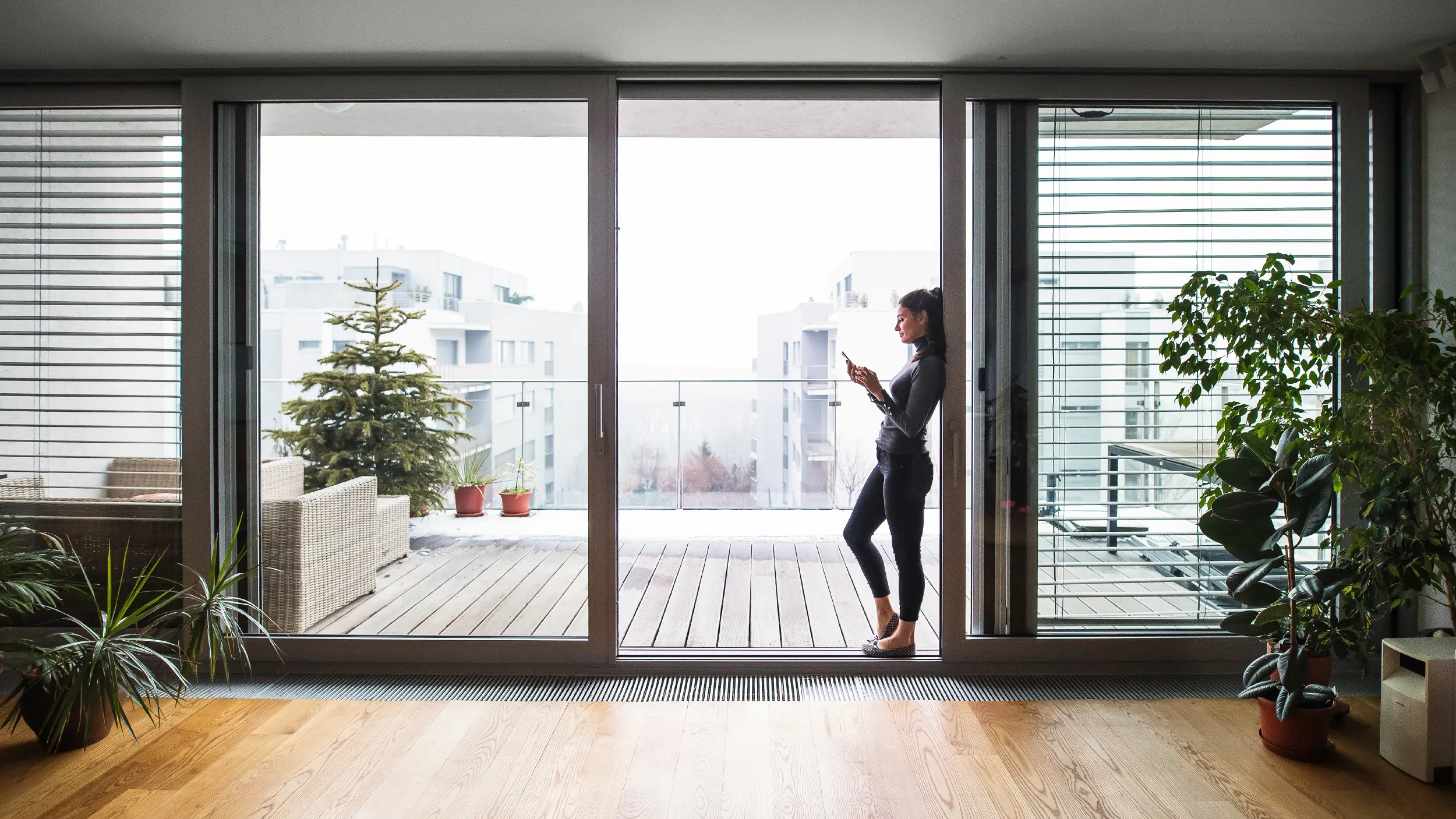 Eine Frau steht in der geöffneten Hebeschiebetür zum Balkon